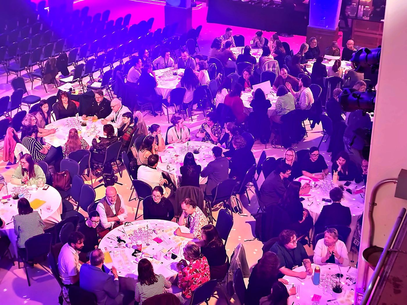 Vu du balcon : le parterre du théâtre rempli de tables rondes, toutes au travail