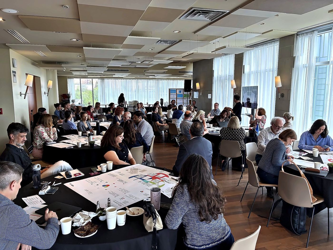 A full room of round tables at Polytechnique Montréal, every table playing at once