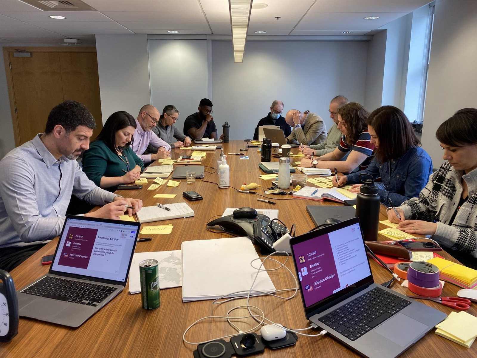 L’équipe de la Cellule Nova+ autour d’une longue table de conférence couverte de post-it, les portables ouverts sur les diapositives de l’atelier