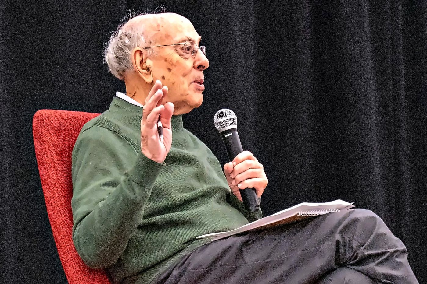 Henry Mintzberg speaking from an armchair, microphone in hand